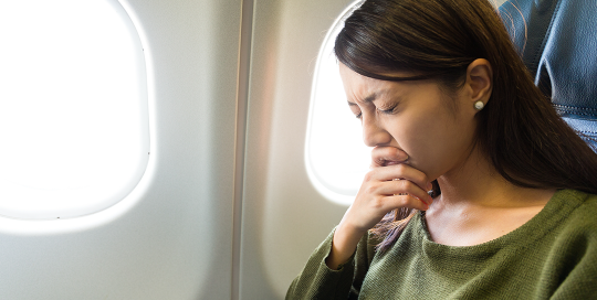 Frau mit Flugangst im Flugzeug. Wie Sie Ängste überwinden können.